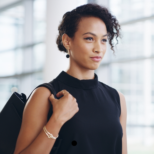 Confident woman in a black blouse with a black purse looking forward